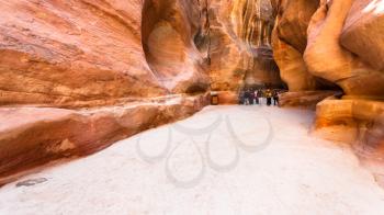 PETRA, JORDAN - FEBRUARY 21, 2012: people on way in Al Siq gorge to ancient Petra town in winter. Rock-cut town Petra was established about 312 BC as the capital city of the Arab Nabataean