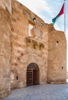 AQABA, JORDAN - FEBRUARY 23, 2012: entrace to Aqaba Fortress (Aqaba Castle, Mamluk Castle, Fort) and Flag of the Arab Revolt. The port of Aqaba was major supply base for the advancing Arab Revolt