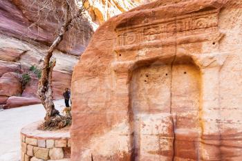 PETRA, JORDAN - FEBRUARY 21, 2012: tourists near stone niches in Al Siq pass to ancient Petra town in winter. Rock-cut town Petra was established about 312 BC as the capital city of the Arab Nabataean