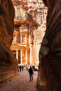 PETRA, JORDAN - FEBRUARY 21, 2012: tourist walk to al-Khazneh temple from Al Siq in Petra town. Rock-cut town Petra was established about 312 BC as the capital city of the Arab Nabataean