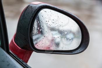 driving car in rain - raindrops on side rearview mirror in rainy day