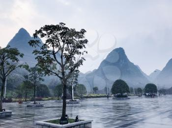 travel to China - wet square and view of karst peaks in Xing Ping town in Yangshuo county in spring rain