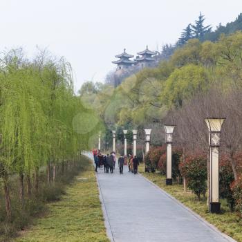 LUOYANG, CHINA - MARCH 20, 2017: tourists walk to temples on East Hill of Chinese Buddhist monument Longmen Grottoes in spring. The complex was inscribed upon the UNESCO World Heritage List in 2000