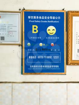 LONGSHENG, CHINA - MARCH 25, 2017: quality certificate (Food Safety Grades Notification according with the document Catering Service Food Safety Supervision) on wall of urban eatery in China