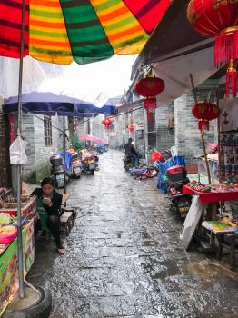 XINGPING, CHINA - MARCH 30, 2017: sellers and stalls on street market in Xing Ping town in Yangshuo county. The town was settled in 265 AD, Xingping is surrounded by great examples of Karst peaks