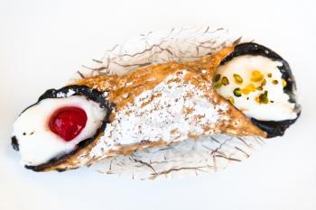 above view of typical sicilian pastry Cannoli sprinkled with confectioner's sugar omn white plate