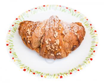 fresh italian croissant filled by nuts and chocolate cream on plate isolated on white background