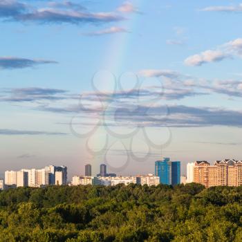 rainbow in blue evening sky over modern houses and Timiryazevsky park in Moscow city in summer