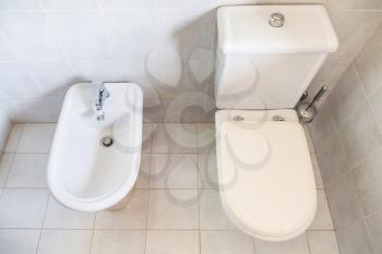 above view of white toilet with bowl drain and bidet in toilet room