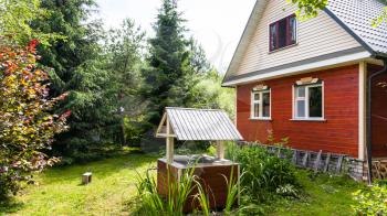view of modern simple cottage and well from backyard in russian country in sunny summer day