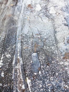frozen footprints on surface of ice-crusted road in cold autumn day