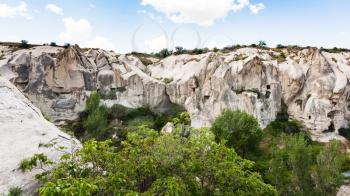 Travel to Turkey - slope of gorge with rock-cut ancient monastic settlement near Goreme town in Cappadocia in spring