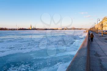 Dvortsovaya Embankment along frozen Neva river and view of Peter and Paul Fortress in Saint Petersburg city in March evening