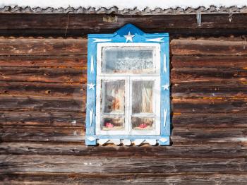 wood log wall with window of old typical russian rural house in sunny winter day in little village in Smolensk region of Russia