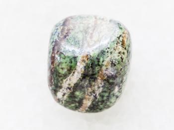macro shooting of natural mineral rock specimen - tumbled chrysotile gemstone on white marble background