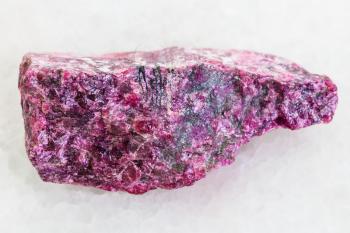 macro shooting of natural mineral rock specimen - rough Eudialyte stone on white marble background from Kukisvumchor, Khibiny Mountains, Kola Peninsula in Russia