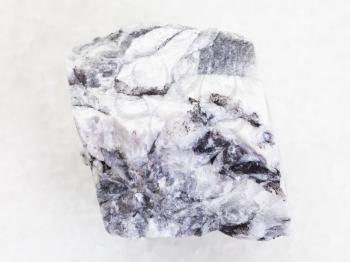 macro shooting of natural mineral rock specimen - rough magnesite stone on white marble background from Satka, South Ural Mountains, Russia