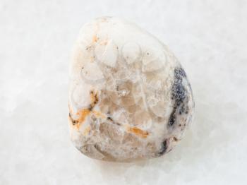 macro shooting of natural mineral rock specimen - tumbled baryte stone on white marble background from North Caucasian region, Russia