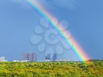 rainbow in blue rainy sky over Moscow city and Timiryazevskiy urban park in sunny day