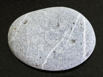 macro shooting of natural mineral rock specimen - tumbled Greywacke sandstone on dark granite background