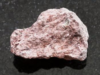macro shooting of natural mineral rock specimen - raw Ash Tuff stone on dark granite background