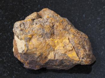 macro shooting of natural mineral rock specimen - raw limonite stone on dark granite background from Olkhinskoye mine, Irkutsk region, Russia