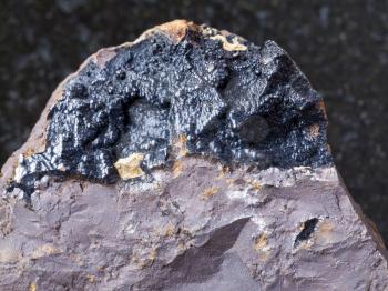 macro shooting of natural mineral rock specimen - goethite ore on limonite stone on dark granite background from Olkhinskoye mine, Irkutsk region, Russia