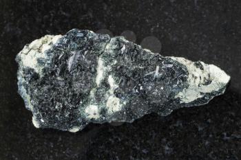 macro shooting of natural mineral stone specimen - rough crystal of hornblende on amphibole - carbonate rock on dark granite background from Korshunovskoe mine of Irkutsk region of Russia