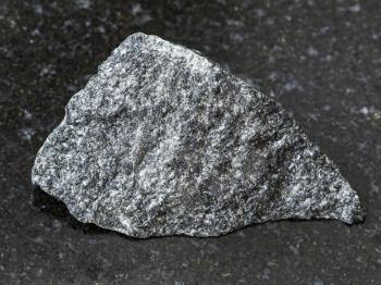 macro shooting of natural mineral rock specimen - rough dolerite (diabase) stone on dark granite background from Raikonkoski district, Karelia, Russia