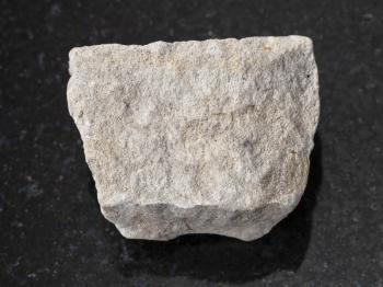 macro shooting of natural mineral rock specimen - rough gray Dolomite stone on dark granite background