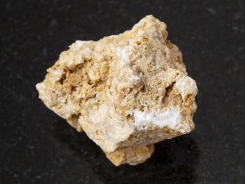 macro shooting of natural mineral rock specimen - raw travertine stone on dark granite background