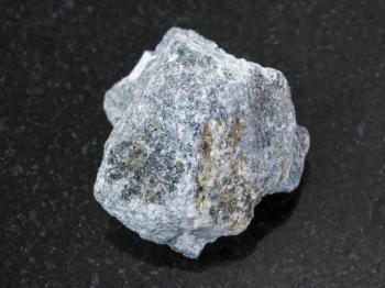 macro shooting of natural mineral rock specimen - rough Soapstone stone ( talc - schist ) on dark granite background