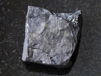 macro shooting of natural mineral rock specimen - rough carbonaceous shale stone on dark granite background
