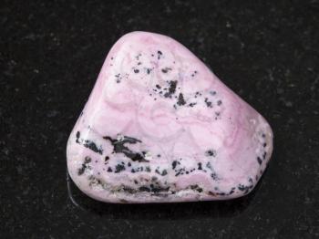 macro shooting of natural mineral rock specimen - polished rhodochrosite gem on dark granite background from Peru