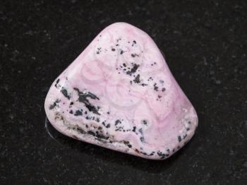 macro shooting of natural mineral rock specimen - raw rhodochrosite gem on dark granite background from Peru