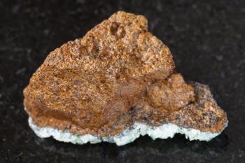 macro shooting of natural mineral rock specimen - rough bog iron ore ( limonite) stone on dark granite background from Taman Peninsula, Russia