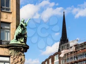 Travel to Germany - outdoor sculpture of old house on Hohe Brucke bridge and steeple of St Nicholas Church (Nikolaikirche) in Hamburg city in september