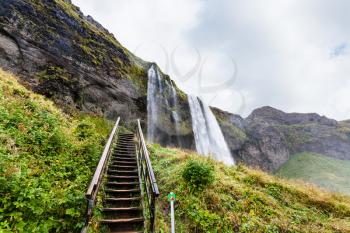 travel to Iceland - steps to cave in Seljalandsfoss waterfall of Seljalands River in Katla Geopark on Icelandic Atlantic South Coast in september