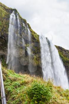 travel to Iceland - green slope and Seljalandsfoss waterfall of Seljalands River in Katla Geopark on Icelandic Atlantic South Coast in september