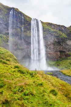 travel to Iceland - green riverbank and Seljalandsfoss waterfall of Seljalands River in Katla Geopark on Icelandic Atlantic South Coast in september