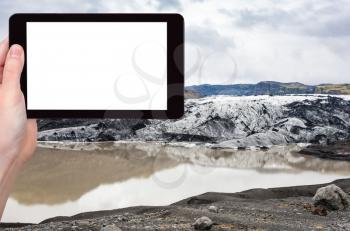 travel concept - tourist photographs Solheimajokull glacier (South glacial tongue of Myrdalsjokull ice cap) in Katla Geopark in Iceland in autumn on tablet with cut out screen for advertising logo