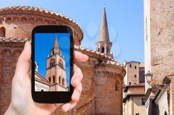 travel concept - tourist photographs tower and Rotonda di san lorenzo and bell tower of Basilica of Sant'Andrea in Mantua city in Italy on smartphone