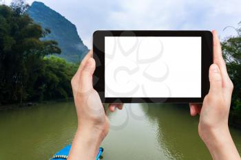 travel concept - tourist photograps river in Yangshuo county in China in spring morning on tablet with cut out screen for advertising logo