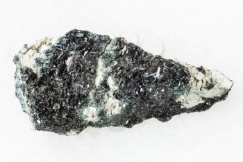 macro shooting of natural mineral stone specimen - rough crystal of hornblende on amphibole - carbonate rock on white marble background from Korshunovskoe mine of Irkutsk region of Russia