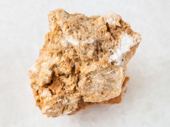 macro shooting of natural mineral rock specimen - raw travertine stone on white marble background