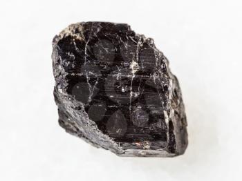 macro shooting of natural mineral rock specimen - crystal of Schorl (black tourmaline) gemstone on white marble background from Madagascar