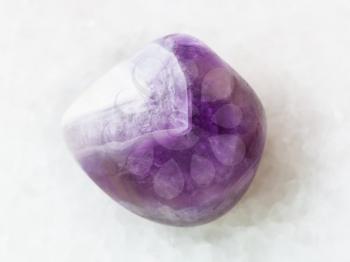 macro shooting of natural mineral rock specimen - polished amethyst gem stone on white marble background from Namibia