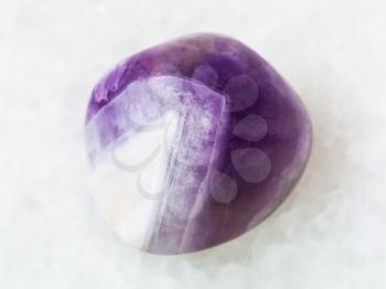macro shooting of natural mineral rock specimen - tumbled amethyst gem stone on white marble background from Namibia