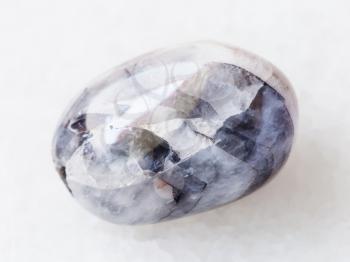 macro shooting of natural mineral rock specimen - polished Stone of Tamerlane (amethyst quartz) gemstone on white marble background from Tajikistan