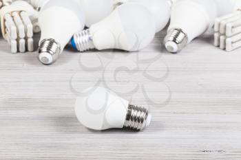 white LED bulb light and several energy-saving lamps on gray wooden board